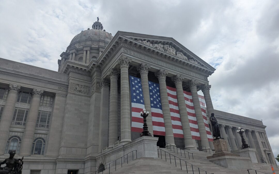 The Missouri State Capitol in Jefferson City with an American flag draped between its columns